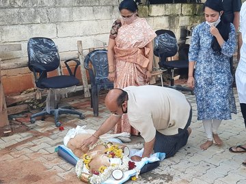 Mr Bommai flanked by family members saying goodbye to his dog Sunny by reaching down to kiss him just before the pet's final rites